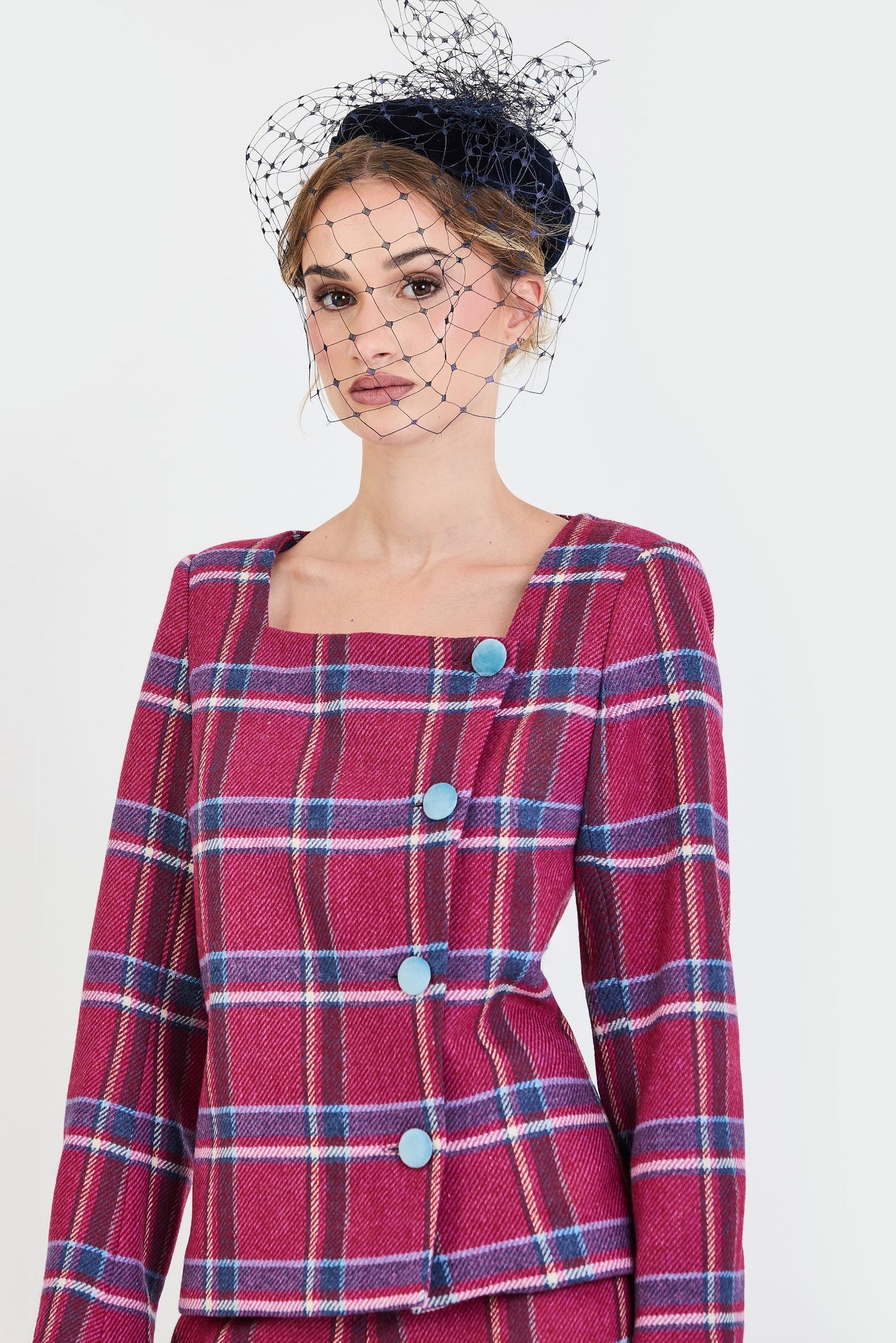 Primer plano de chaqueta de invitada de la colección Otoño Invierno 2025-2026 de Zinnia Brand con estampado de cuadros en tonos fucsia y azul. Diseño estructurado con escote cuadrado y botones de terciopelo azul que aporta elegancia contemporánea.
