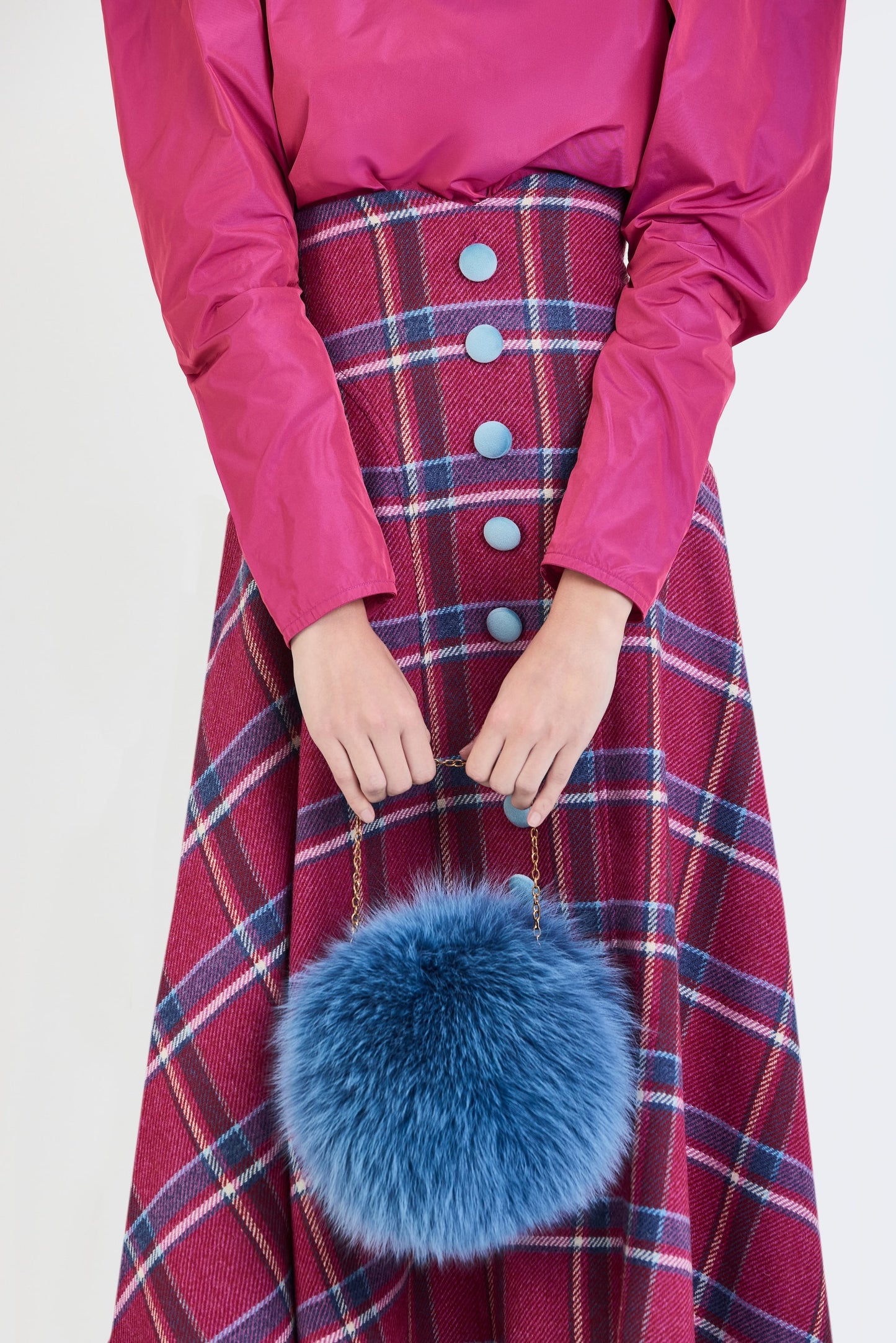 Plano detalle de la falda de invitada de la colección Otoño Invierno 2025-2026 de Zinnia Brand con blusa en tono fucsia de mangas abullonadas y falda midi de cuadros en tonos fucsia y azul. Un diseño sofisticado y femenino que combina elegancia contemporánea y estilo para eventos especiales.
