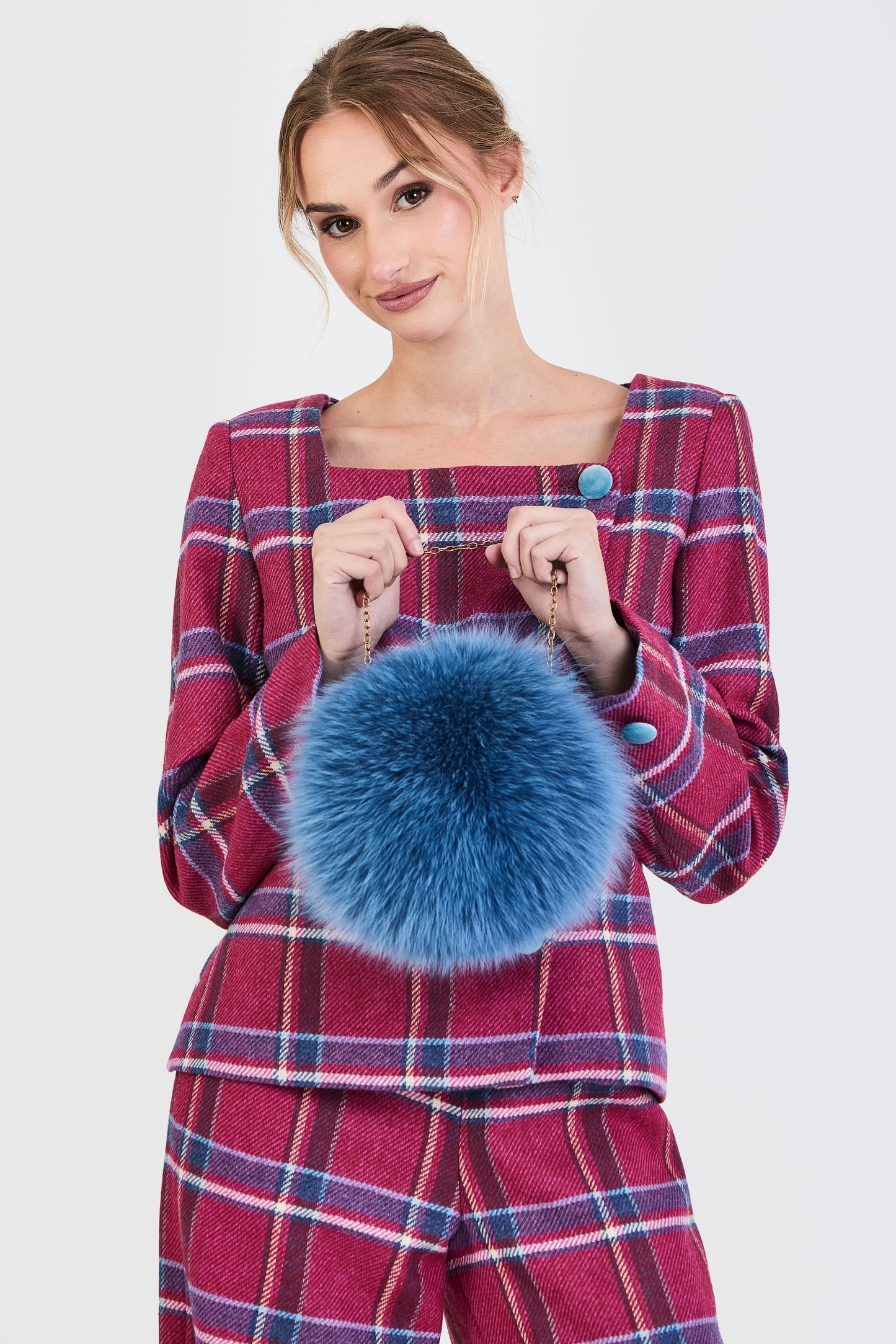 Primer plano del traje de invitada de la colección Otoño Invierno 2025-2026 de Zinnia Brand con estampado de cuadros en tonos fucsia y azul. Diseño estructurado con escote cuadrado y botones de terciopelo azul  y pantalón recto del mismo estampado que aporta elegancia contemporánea. 
