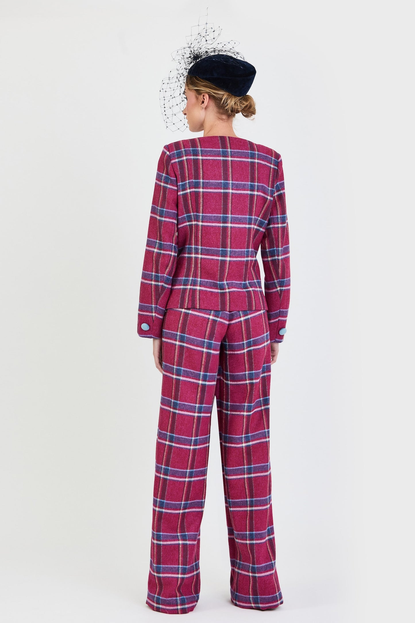 Plano de espalda del traje de invitada de la colección Otoño Invierno 2025-2026 de Zinnia Brand con estampado de cuadros en tonos fucsia y azul. Diseño estructurado con escote cuadrado y botones de terciopelo azul  y pantalón recto del mismo estampado que aporta elegancia contemporánea